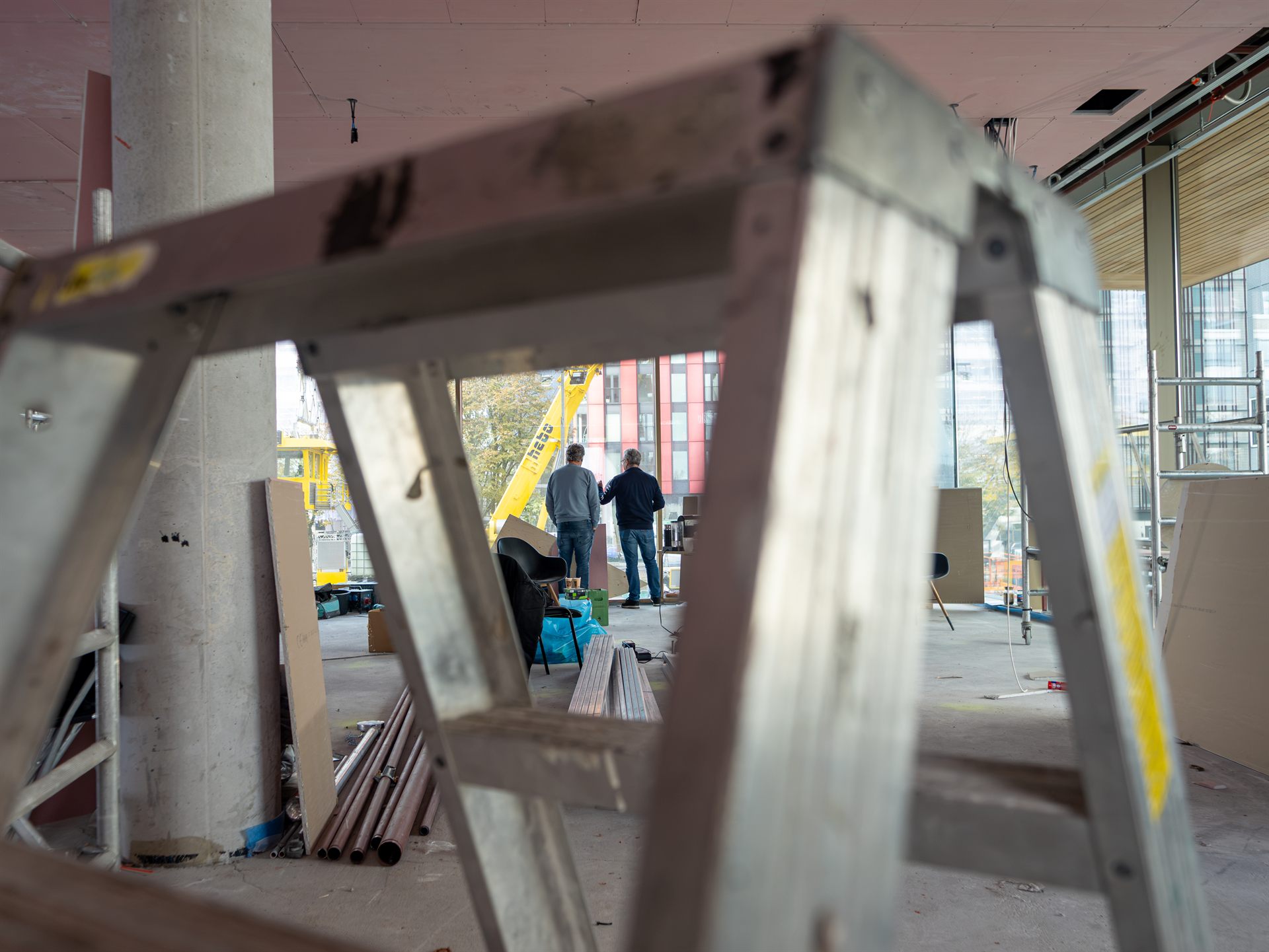 Man bekijkt de voortgang van de verbouwing bij de glazen gevel van Restaurant Fred.